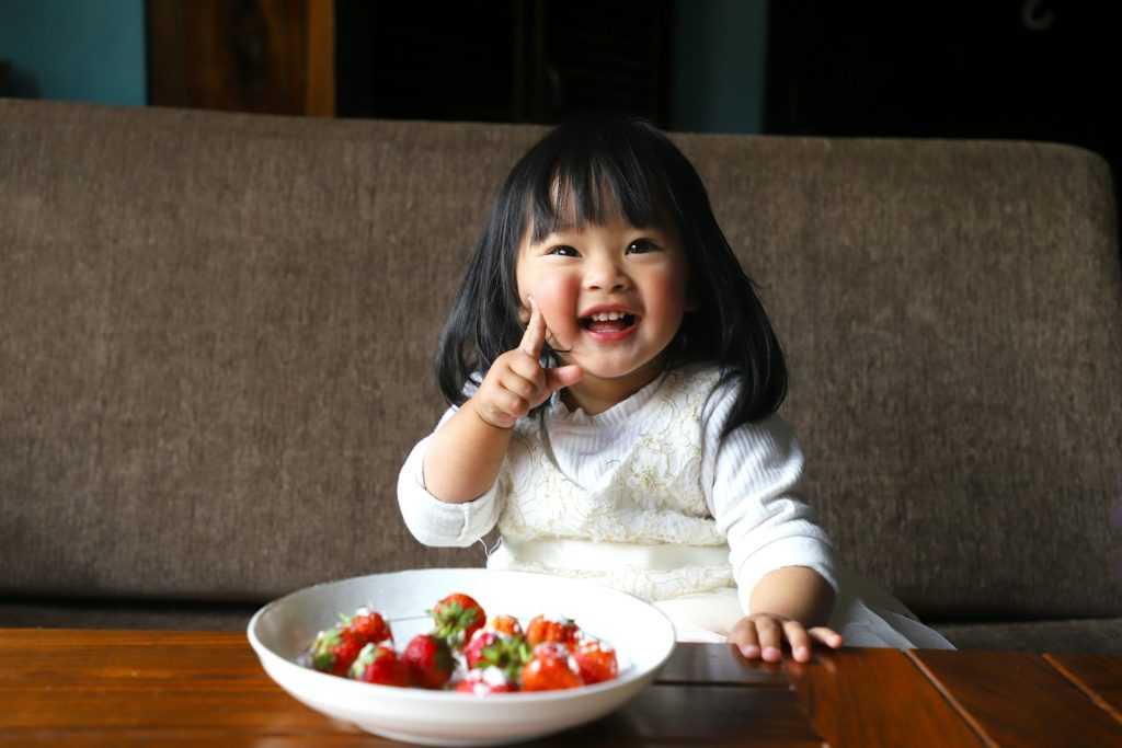 Happy girl enjoying a bowl of fresh fruit